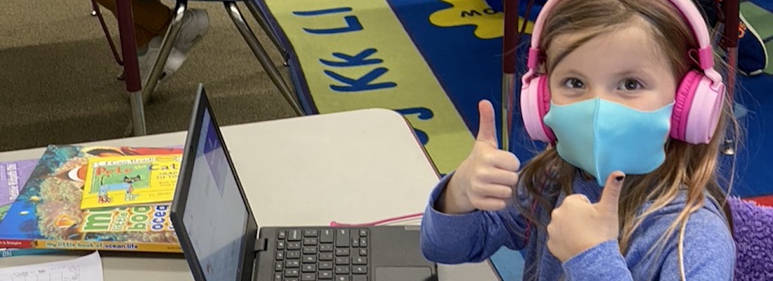 Student using laptop computer posing with 2 thumbs up