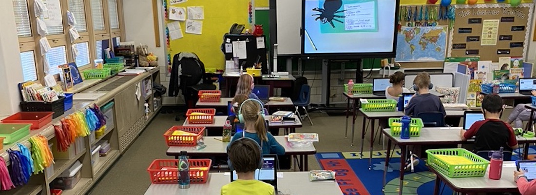 Classroom of students with headphones on using laptops