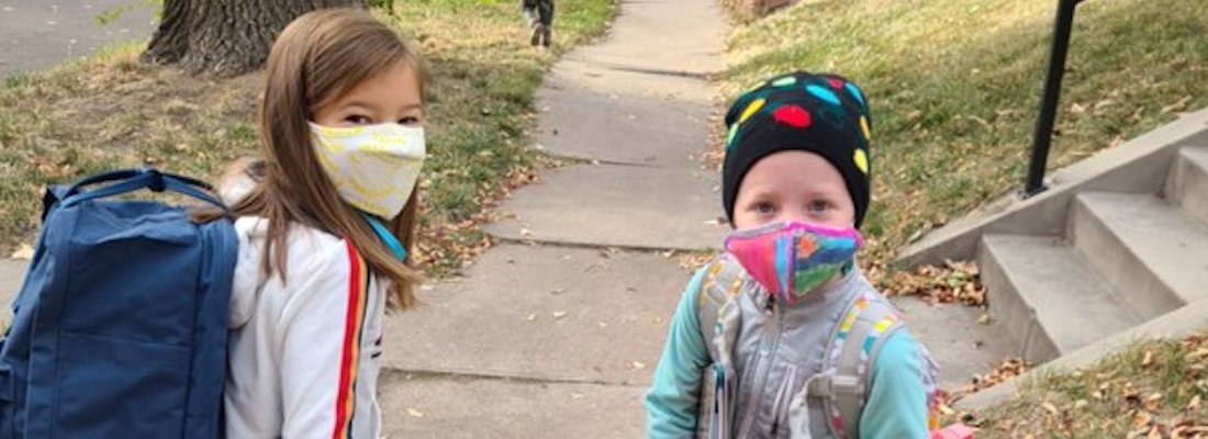 2 students posing outside wearing masks